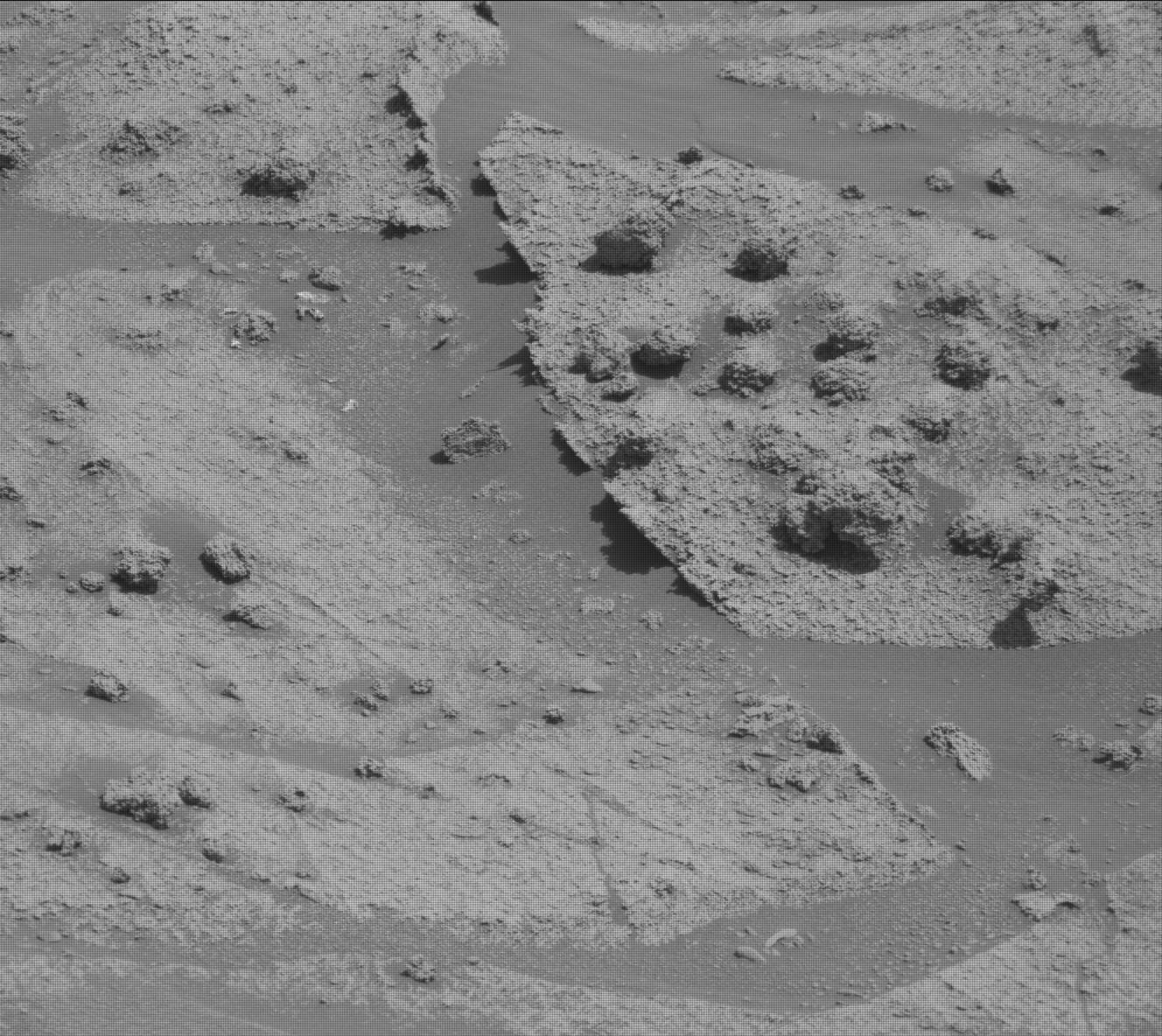 This is a black and white image of the rocky, sandy surface of Mars. The surface appears to be smooth and there are small chunks of rocks in places. 