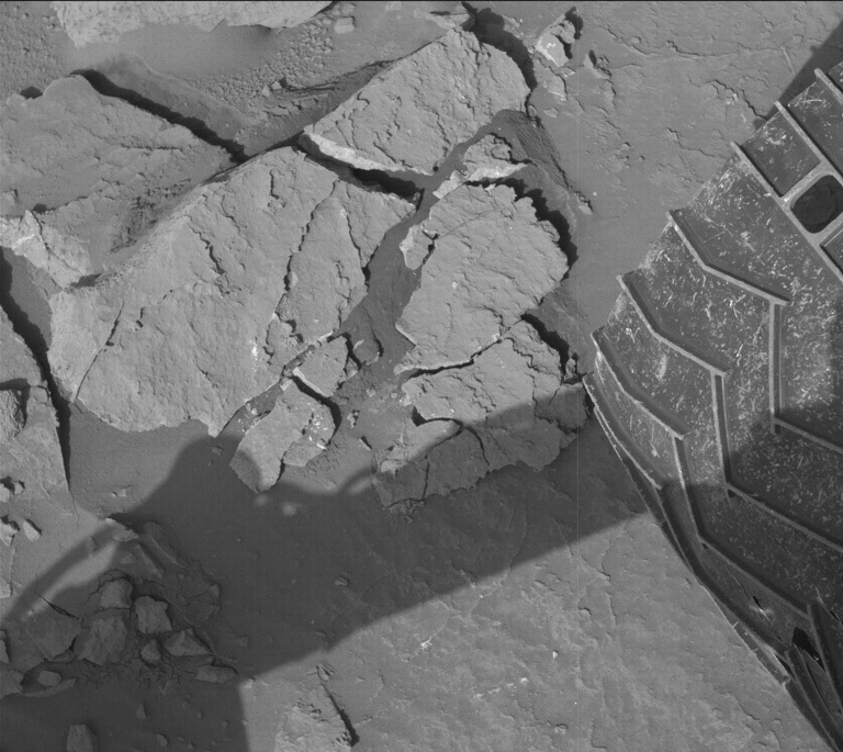 A bedrock slab on Mars and part of a rover's wheel