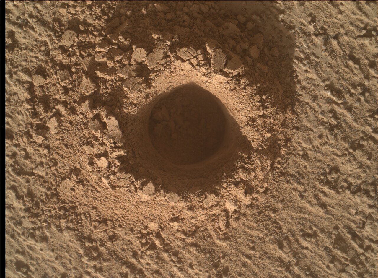 This is a close up image of a drill hole made by Curiosity. The sand surrounding and inside the drill site is crumbly and smooth. 