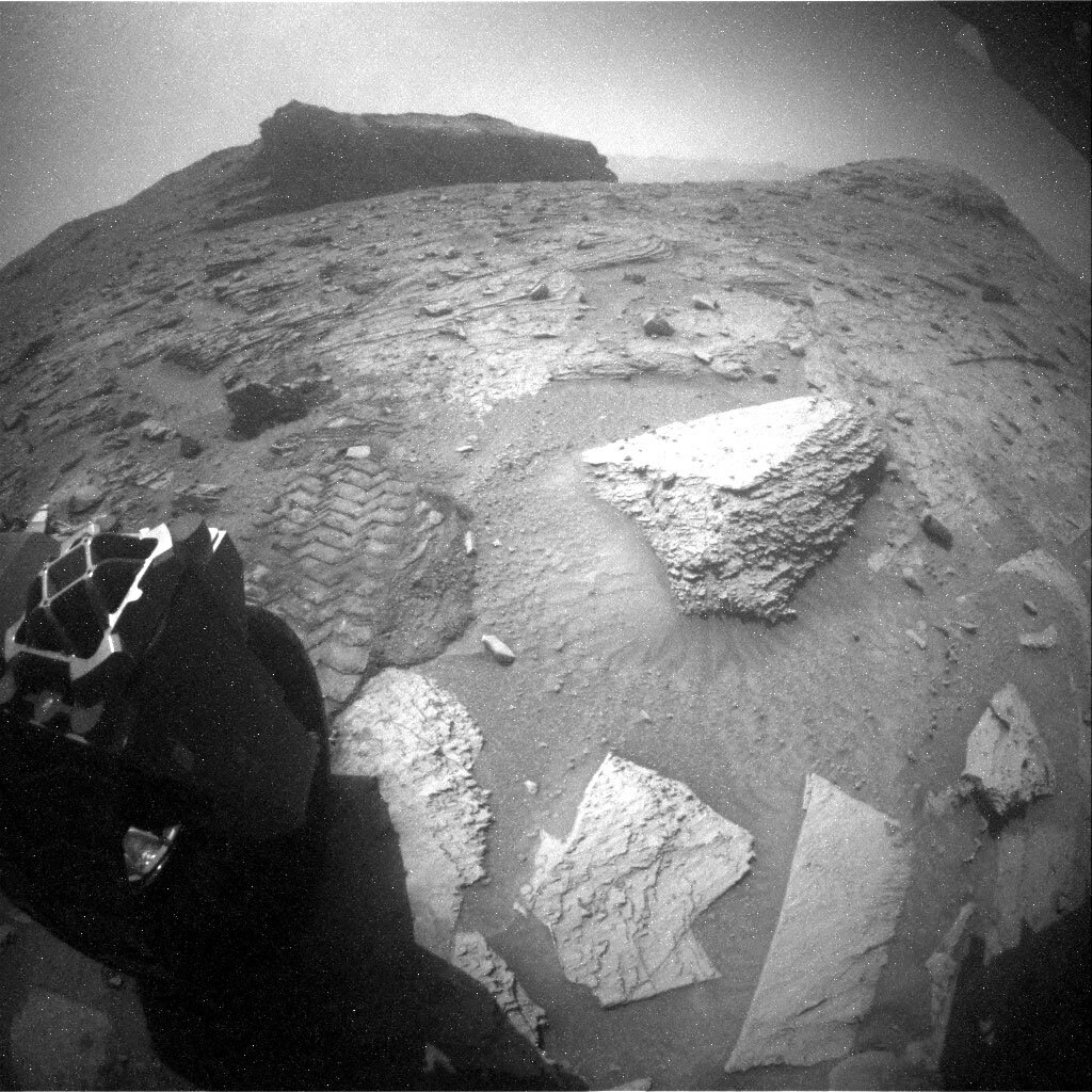 This image shows the rear hazard camera view onto the landscape. Remember that the hazard camera is mounted below the rover body, so we are looking from very low to the ground upwards. This image was taken by Rear Hazard Avoidance Camera (Rear Hazcam) onboard NASA's Mars rover Curiosity on Sol 3329.