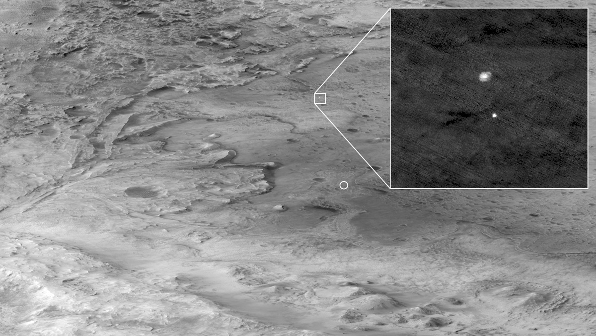 in this image, the descent stage holding NASA’s Perseverance rover can be seen falling thorough the Martian atmosphere, its parachute trailing behind