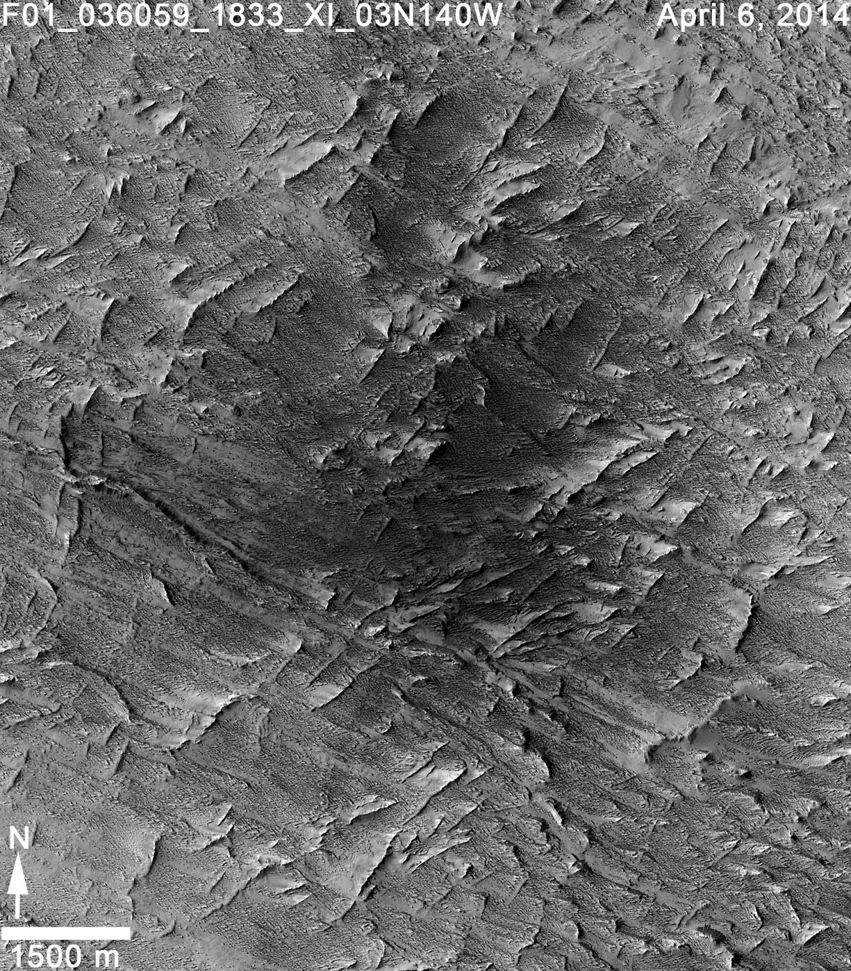 This April 6, 2014, image from the Context Camera on NASA's Mars Reconnaissance Orbiter was taken as a follow-up to discovery of a possible 2012 impact scar in images from the orbiter's Mars Color Imager. It reveals two craters within the darkened area (at center of the inscribed rectangle).