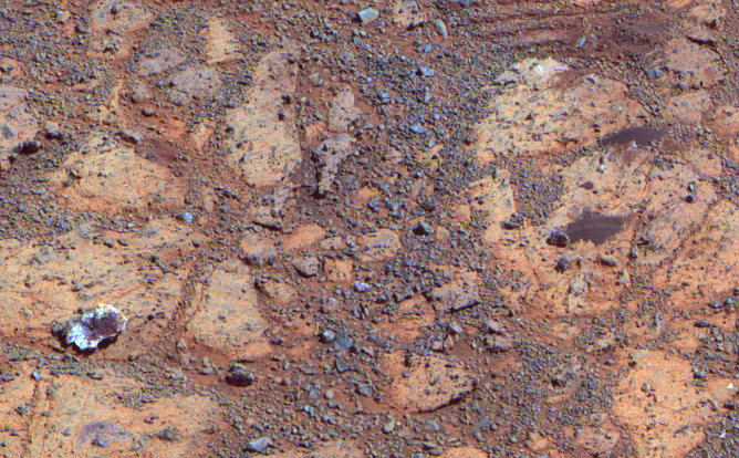 A rock with a white edge and a red center reminds us of a jelly donut in a box from the local donut shop in this image taken by Opportunity on February 4, 2014. Named "pinnacle Island" by Opportunity's science team, this rock mysteriously appeared in an image where it had not been 4 days earlier. Scientists believe that opportunity drove over and broke a rocks in the upper part of this image, sending that piece of pastry rolling downhill.