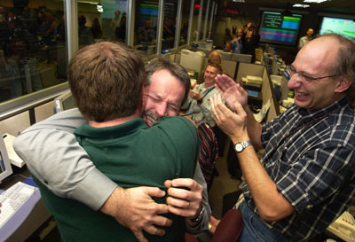 Entry, descent and landing manager, Rob Manning (facing camera), hugs Richard Cook, the current Mars Exploration Rover project manager after Opportunity's successful landing at Meridiani Planum, Mars.